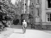 James Robertson-Justice walking from President Hall past the Clock Tower.